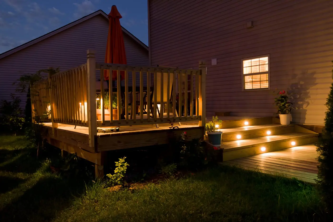 Wood deck at night with low-voltage lighting on the stairs and railing