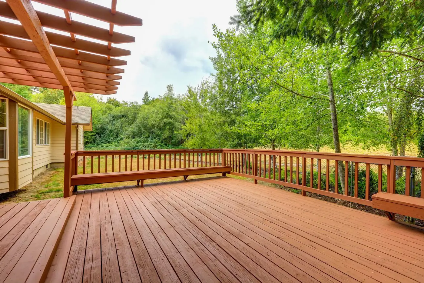 Redwood-toned deck with matching railing and attached pergola