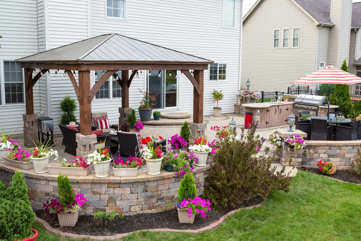 Backyard gazebo with string lights over a paver patio and outdoor kitchen