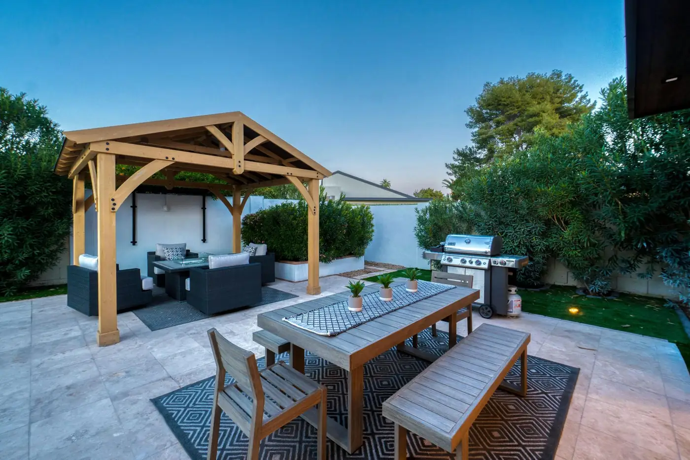 Timber pavilion with lounge seating over a stone patio at dusk