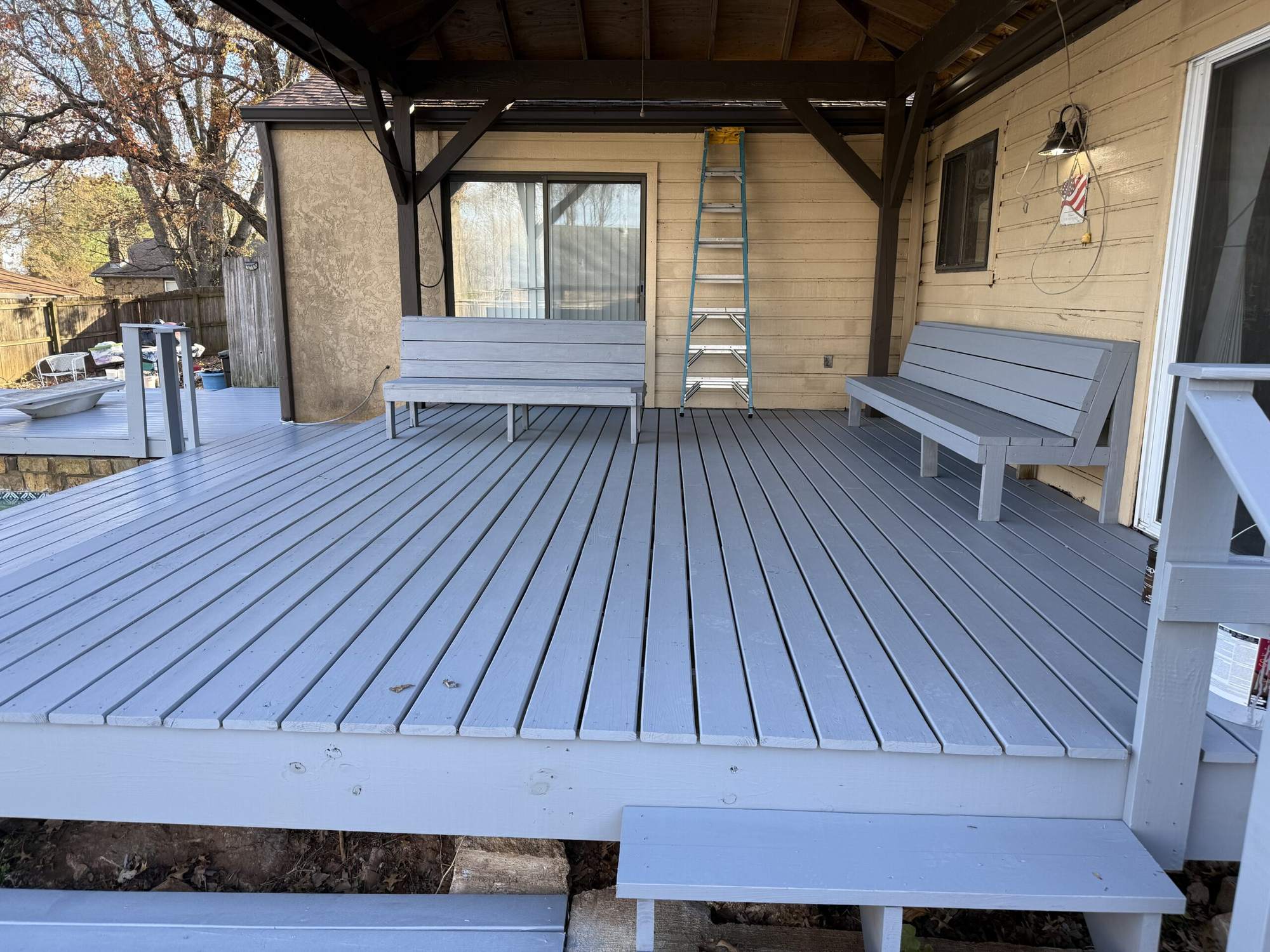 Repainted gray wood deck with built-in benches under a covered patio roof
