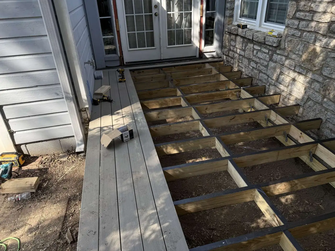 New pressure-treated joist framing with protective tape during a deck replacement