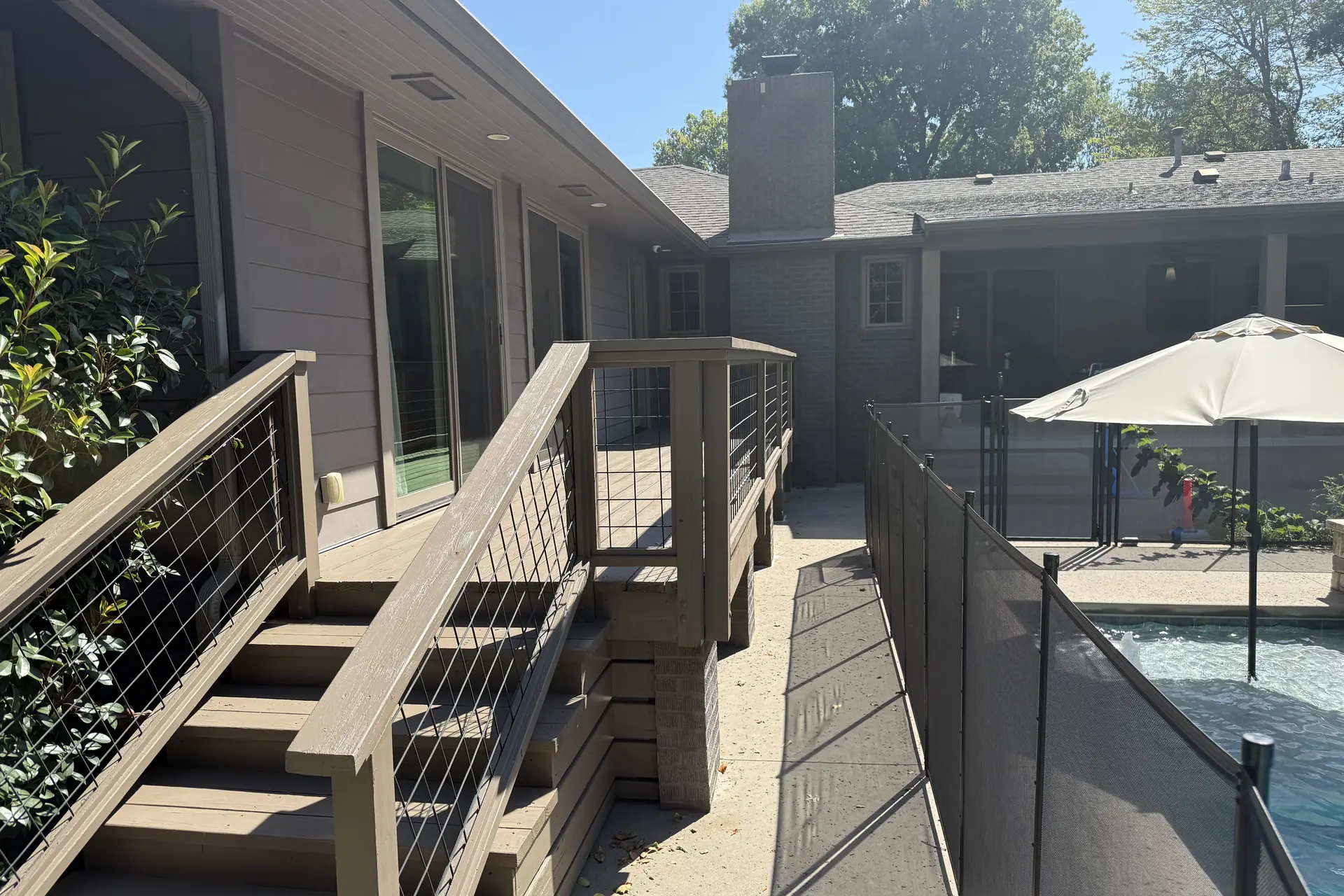Composite deck stairs with cable railing beside a pool fence
