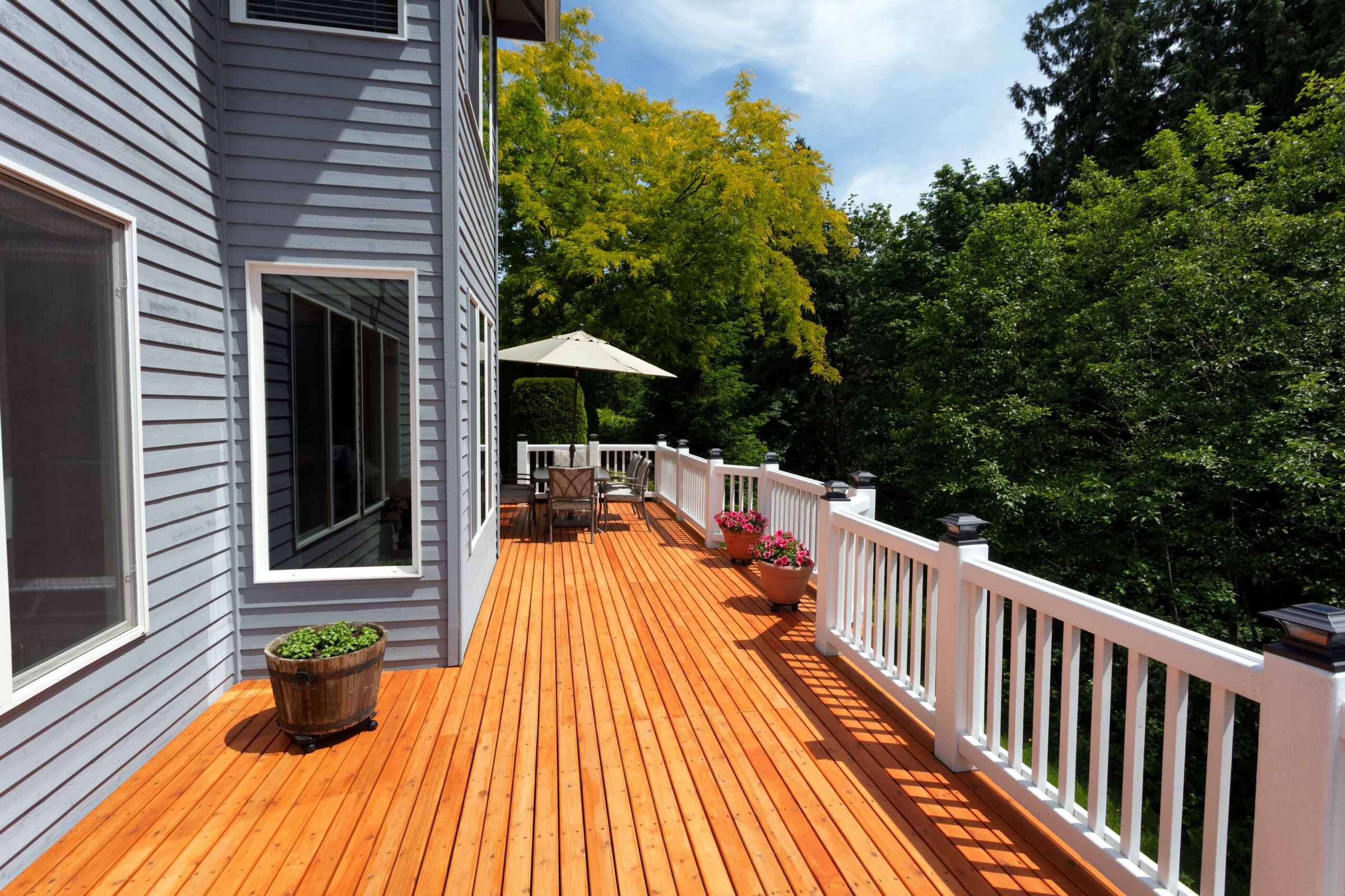 New cedar deck with white railings and a shaded dining area behind a two-story Nashville home